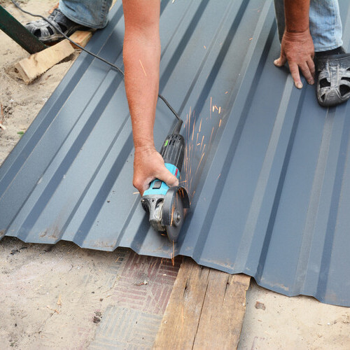worker cutting metal roofing