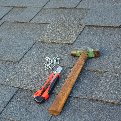 tools on top of an asphalt shingle roof