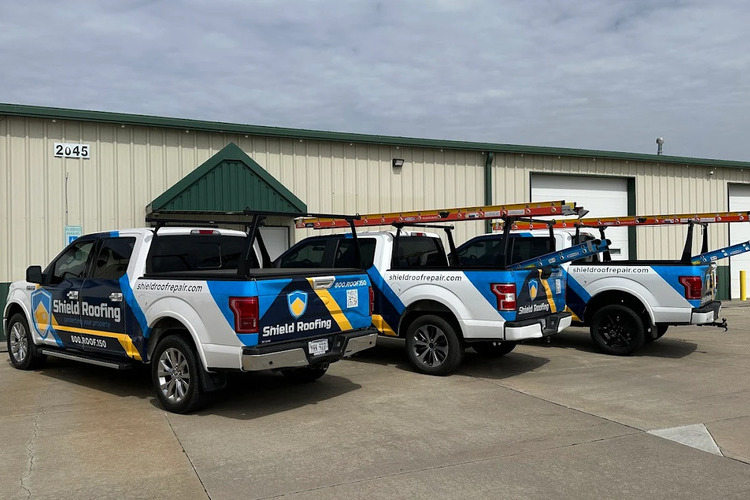 three roofing trucks in front of a warehouse