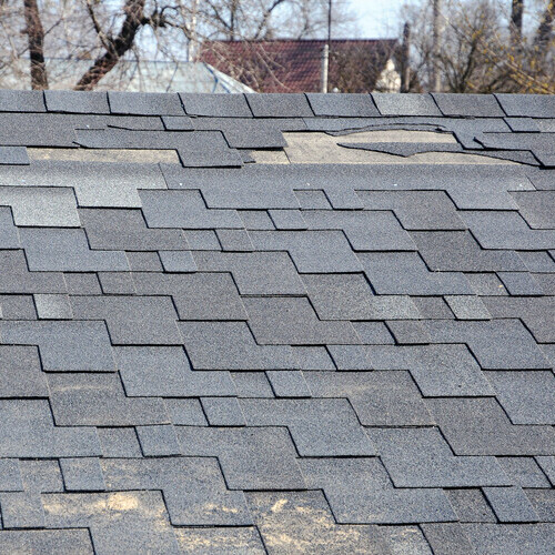 a roof with missing and wind damaged shingles